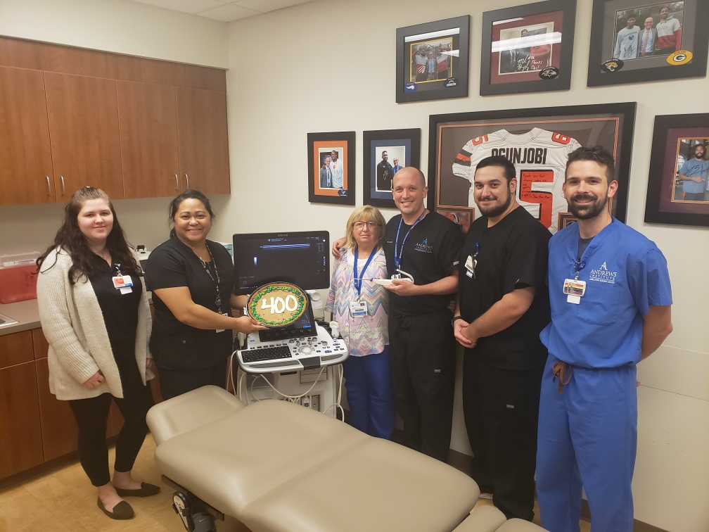 Doctor celebrating 400 procedures with five team members holding a giant cookie
