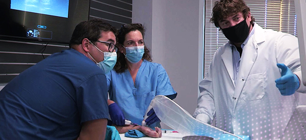 Physician pointing at ultrasound machine teaching two other physicians