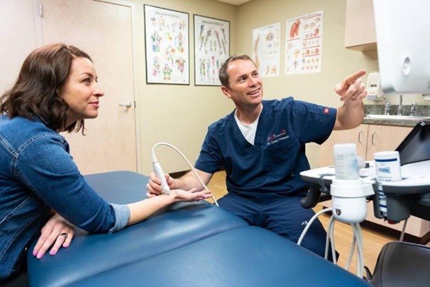 Physician scanning patients wrist for carpal tunnel syndrome and pointing at the ultrasound monitor