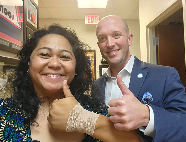 A female and male smiling holding a thumbs up.