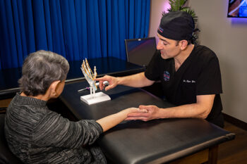 Dr. Ryan Grabow showing a patient anatomy in the carpal tunnel with skeleton hand